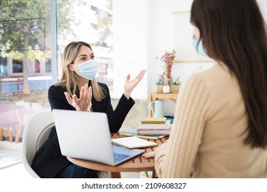 Two Women Wearing Face Masks Have A Business Meeting Inside An 