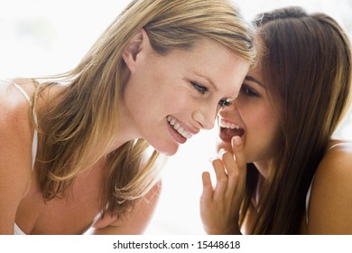 Two Women Whispering And Smiling