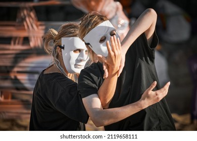 Two Women In White Theatre Mask Dancing On Art Theatrical Festival. Outdoor Dance Performance Of Two Girls Dancers In Total Black Clothes Style. Outdoor Art Theatrical Performance Festival