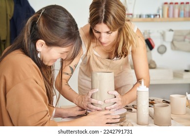 Two women working with clay in a pottery workshop. Craft, art and hobbies concept. - Powered by Shutterstock