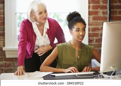 Two Women Working At Computer In Contemporary Office