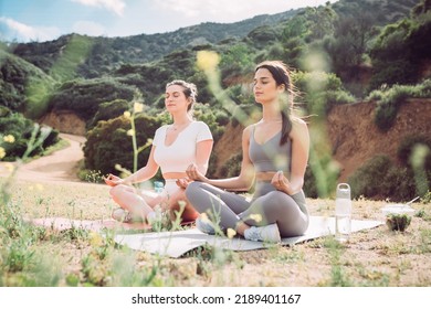 Two Women In Workout Clothing Meditating In Rugged, Outdoor Setting