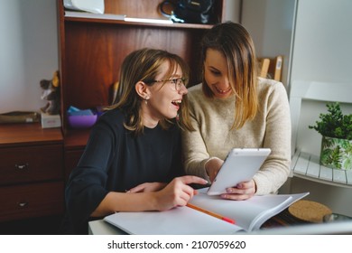 Two Women Young Caucasian Female Student Sitting At Home With Her Sister Looking Excited To The Digital Tablet Checking Entry Exam Results Happy Smiling Young Woman Student Happy With Study Results