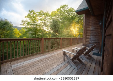 Two wooden adirondack chairs on cabin porch facing the forest overlook - Shutterstock ID 2380001289
