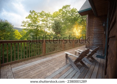 Two wooden adirondack chairs on cabin porch facing the forest overlook