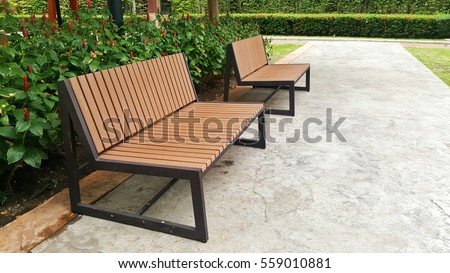 Two wooden benches on cement floor at park