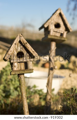 Two wooden bird houses in sunshine, one in focus, one out.