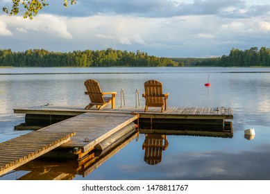 Two wooden chairs at Sunset on a pier on the shores of the calm Saimaa lakein Finland - 4