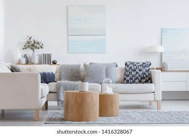 Dos mesas bajas de madera con una maceta delante del sofá de esquina gris en un interior de estilo moderno