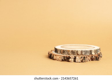 Two wooden discs stacked as a podium on beige background for product presentation. Copy space.