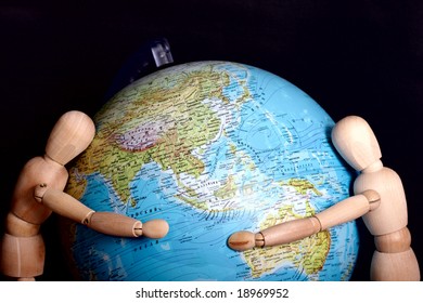 Two Wooden Dolls Puts Arms Around Globe Over Dark