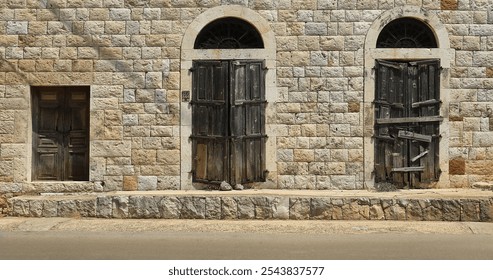 Two wooden doors closed with panes with arches on top and a small door on the side, typical Lebanese architectural details. - Powered by Shutterstock