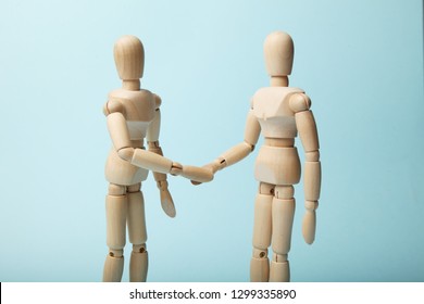 Two Wooden Figures Of Man Shake Hands.