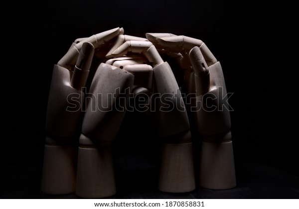 Two wooden hands clasped together while two other\
hands are girding them