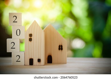 Two Wooden Houses Model With Wooden Block Number 2022 Concept To Show New House, New Year Property, Property Concept Isolated On Green Bokeh Background.