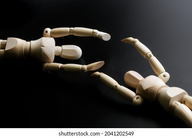 Two wooden mannequins hold out their hands to each other against a dark background. The concept of loneliness, gender identity and finding a partner. Close-up - Powered by Shutterstock