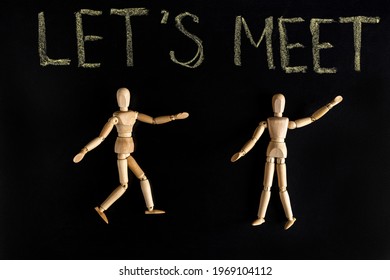 Two Wooden Mannequins And Let's Meet Lettering On Black Background