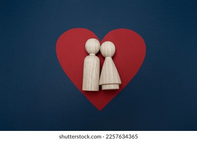 Two wooden peg dolls couple lying on a red heart together with navy blue background. Love, romantic, Valentine's Day, heart shape. - Shutterstock ID 2257634365