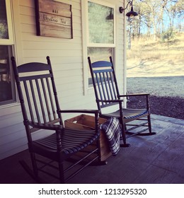 Two Wooden Pretty Rocking Chairs On Front Porch Of A Farm House.