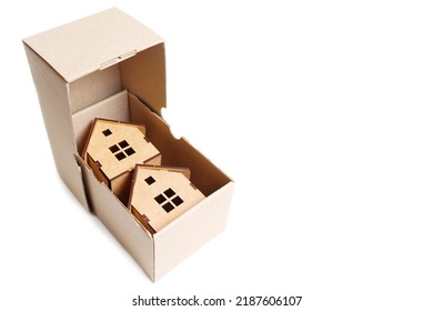 Two Wooden Toy Houses Inside A Small Shipping Box. Creative Moving In Concept.