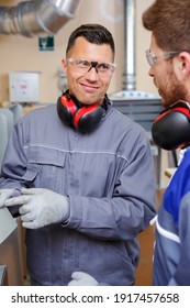 Two Worker In Blue Dungarees In A Carpenters Workshop