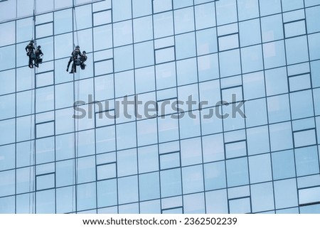 Two Worker Cleaning The Windows Of A High Rise Building Or Skyscraper, With Copy Space