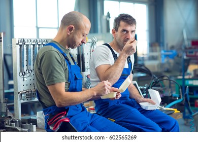 Two Worker In Factory Have A Break On Work Bench