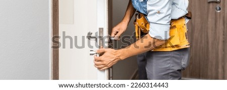 Two worker hands of carpenter at lock installation into wood door