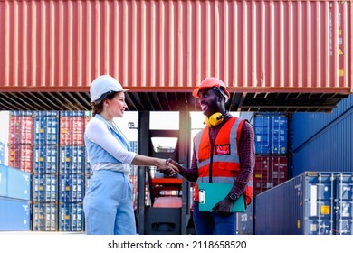 Two Worker Wearing Safety Helmet Shaking Hands At Logistic Shipping Cargo Containers Yard. African American Engineer Man Having Hand Shack With His Beautiful Young Woman Boss After Work Discussion