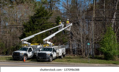 Two workers in a cherry picker bucket working on electrical wires