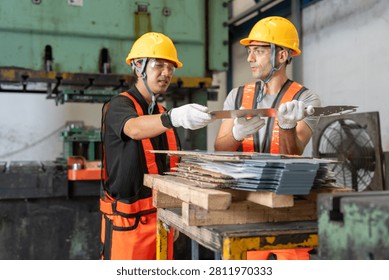 Two workers collaborating in a factory setting inspecting metal sheets with safety gear and equipment