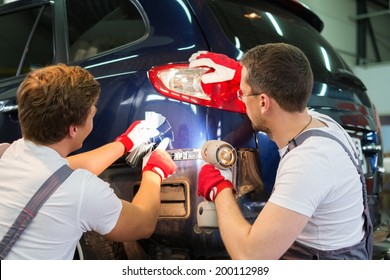 Two workers with colour samples choosing correct shade in a car body workshop 