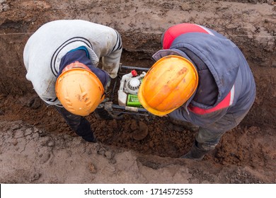 Two Workers Digging Hole For Fence Post. Construction Fence Installation