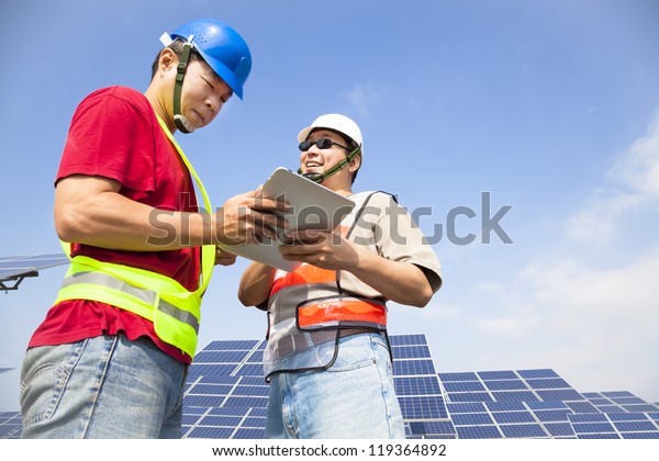 two workers discussing with tablet pc before solar power station