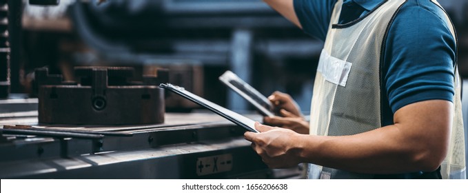 Two workers at an industrial plant with a tablet in hand and document plan, Engineer looking of working at industrial machinery setup in factory. - Powered by Shutterstock