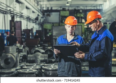 Two Workers At An Industrial Plant With A Tablet In Hand, Working Together Manufacturing Activities