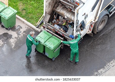 two workers loading mixed domestic waste in waste collection truck - Shutterstock ID 1825633037