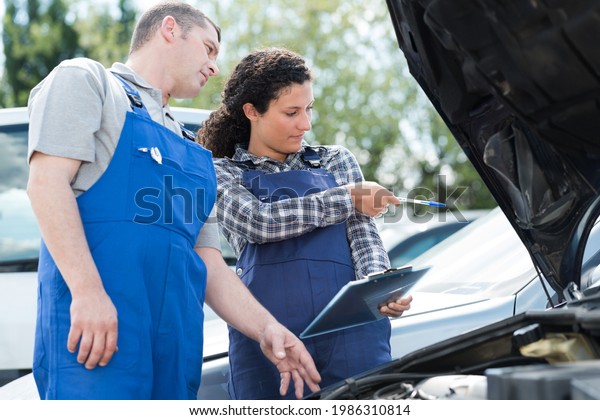 two workers\
looking at car documents\
outdoors