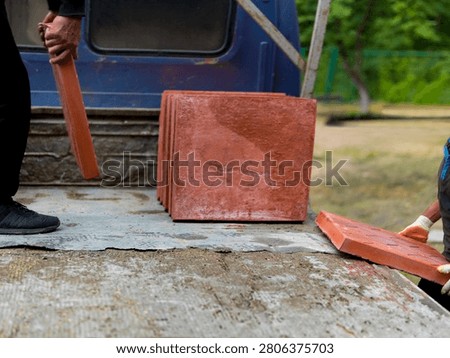 two workers manual offloading of heavy tile pallets from a truck