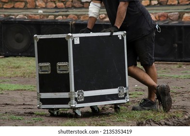 Two Workers Moving A Box, Music Speakers And Audio Console For Recital. Team Setting Up Stage For A Rock Show