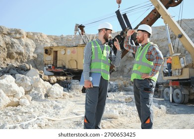 Two workers and quarry in background.