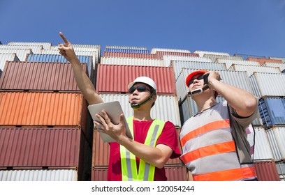 two workers with tablet pc and standing before stack of containers