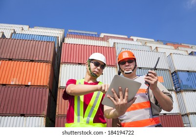 two workers with tablet  and standing before stack of containers