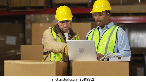 Two Workers In Warehouse Use Laptop Computer