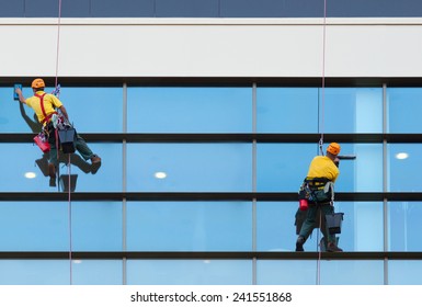 Two workers washing windows of the modern building.