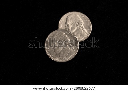 two worn five-cent coins on a black background, two old worn scratched 5-cent coins in close-up on black velvet, close up
