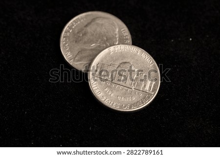 two worn five-cent coins on a black background, two old worn scratched 5-cent coins in close-up on black velvet, close up