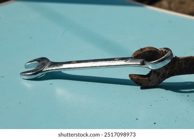 two wrenches with different textures. rusty and unrusted bolt openers are compared into one. the difference between unrusted and rusty iron on a light blue background, high angle