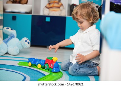 A Two Year Old Child Playing In His Room With A Toy Train