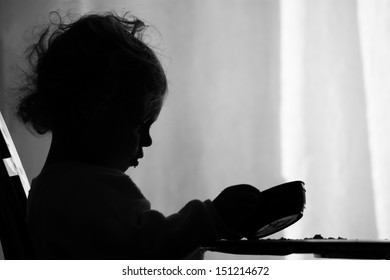 A Two Year Old Girl Is Sadly Looking Into Her Empty Bowl Wishing She Had More To Eat. / Hunger